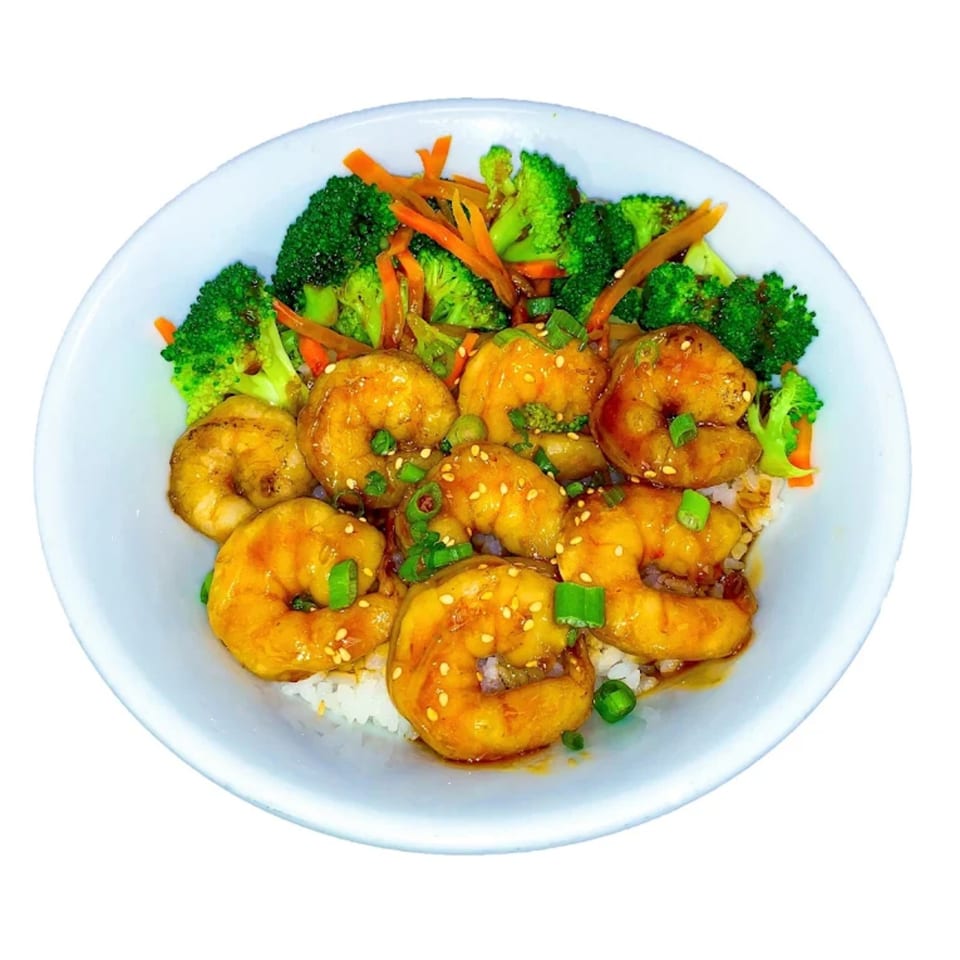 A white bowl filled with shrimp, broccoli, carrots, and rice, garnished with sesame seeds and green onions.